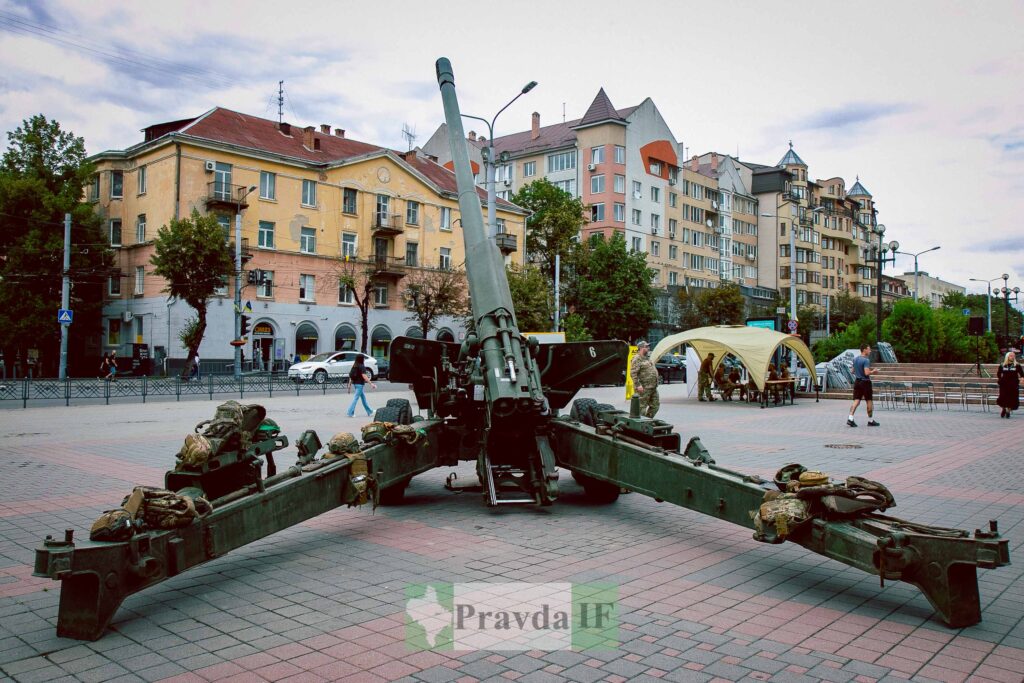 Гармата на площі в місті, оточена людьми.