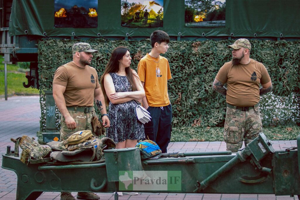 Група людей поруч з військовослужбовцем у формі.