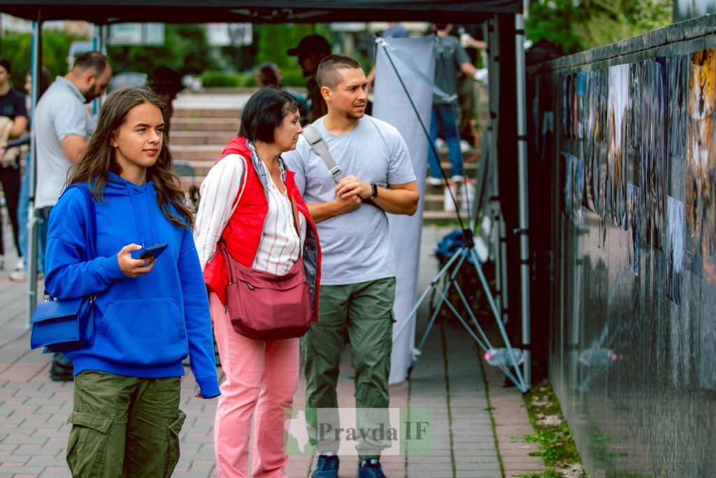 Люди дивляться на фотографії у вуличній галереї