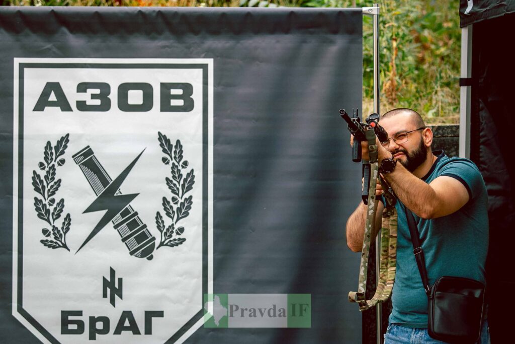 Чоловік зі зброєю біля символіки Азов