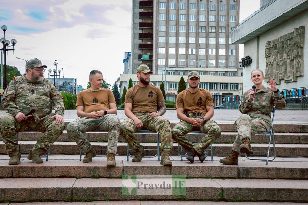 Група військових на стільцях перед будівлею