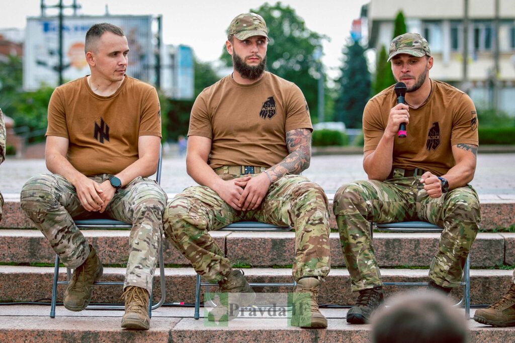 Троє чоловіків у військовій формі на вулиці.