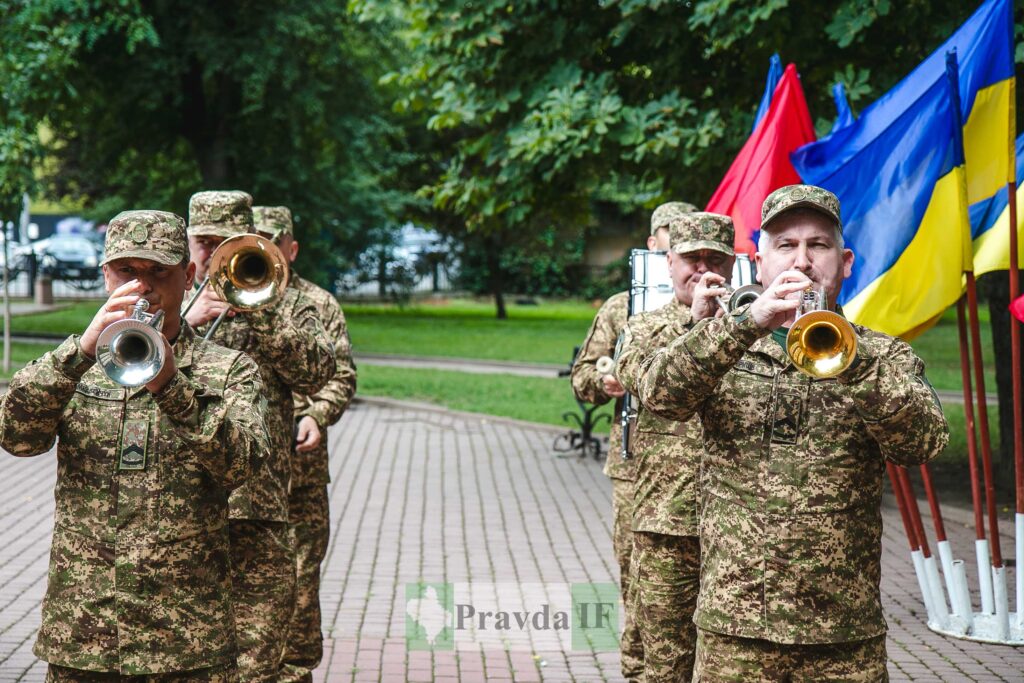 Військовий оркестр виконує марш, прапори України