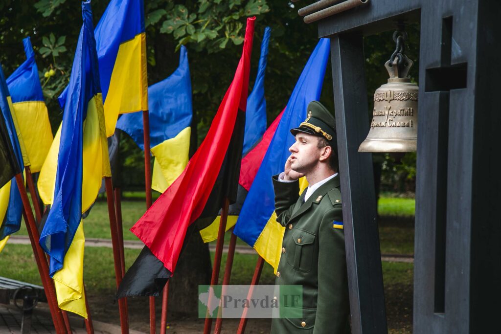 Український військовий біля прапорів та дзвона