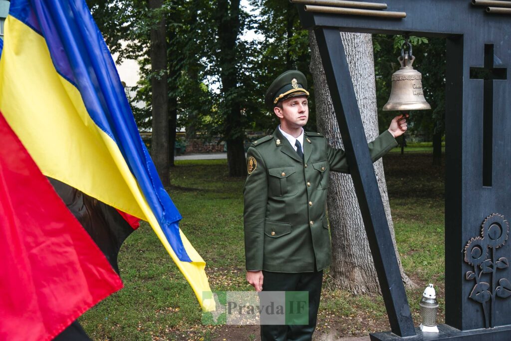 Військовий біля дзвону і прапора в парку