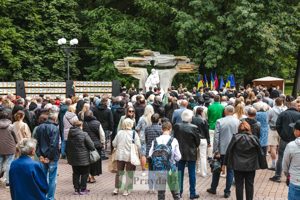 Люди на меморіальному заході біля пам'ятника.