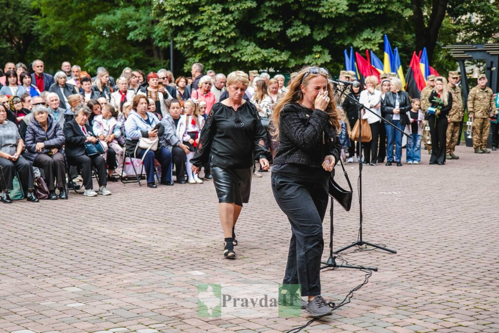 Жінки на мітингу з прапорами України на фоні.