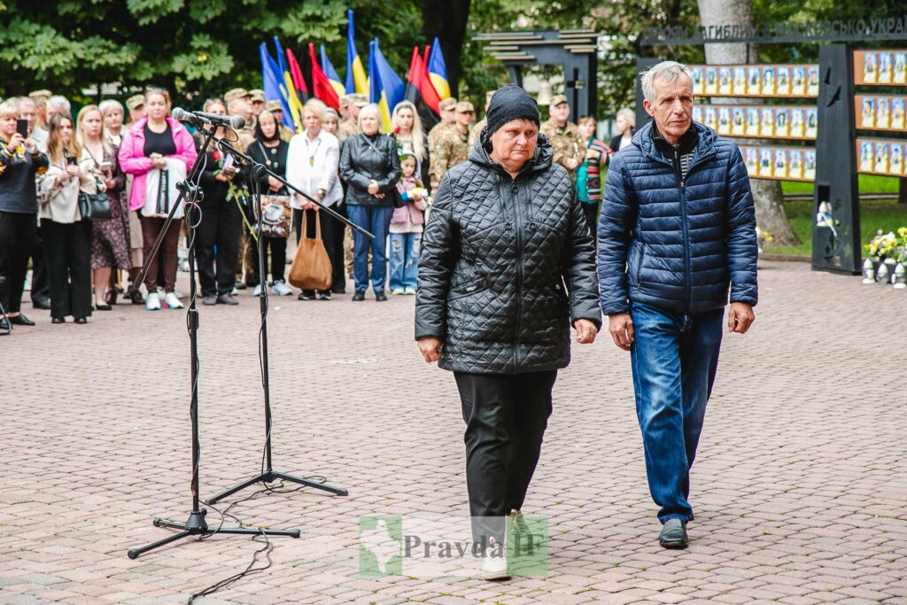 Люди на вулиці перед мікрофоном, прапори України.