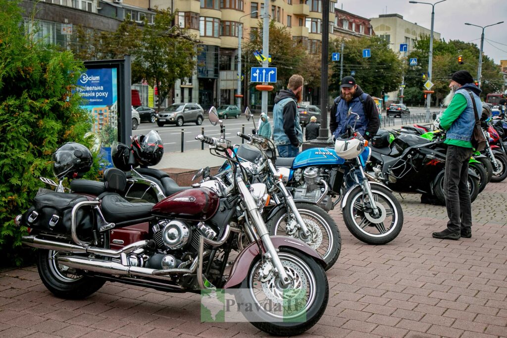 Мотоцикли припарковані на вулиці біля людей.