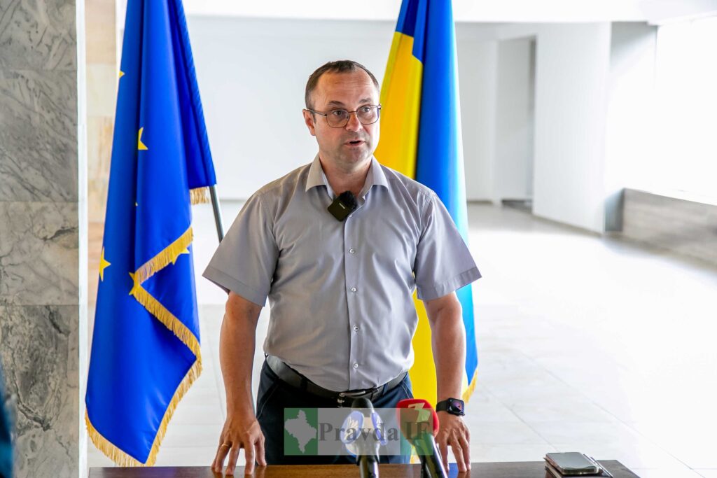 Чоловік виступає перед прапорами України та ЄС.