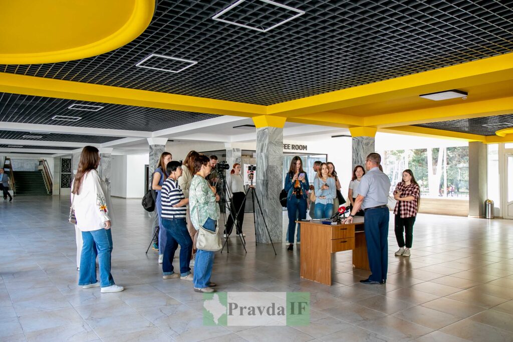 Пресконференція в сучасній залі зі жовтою стелею.