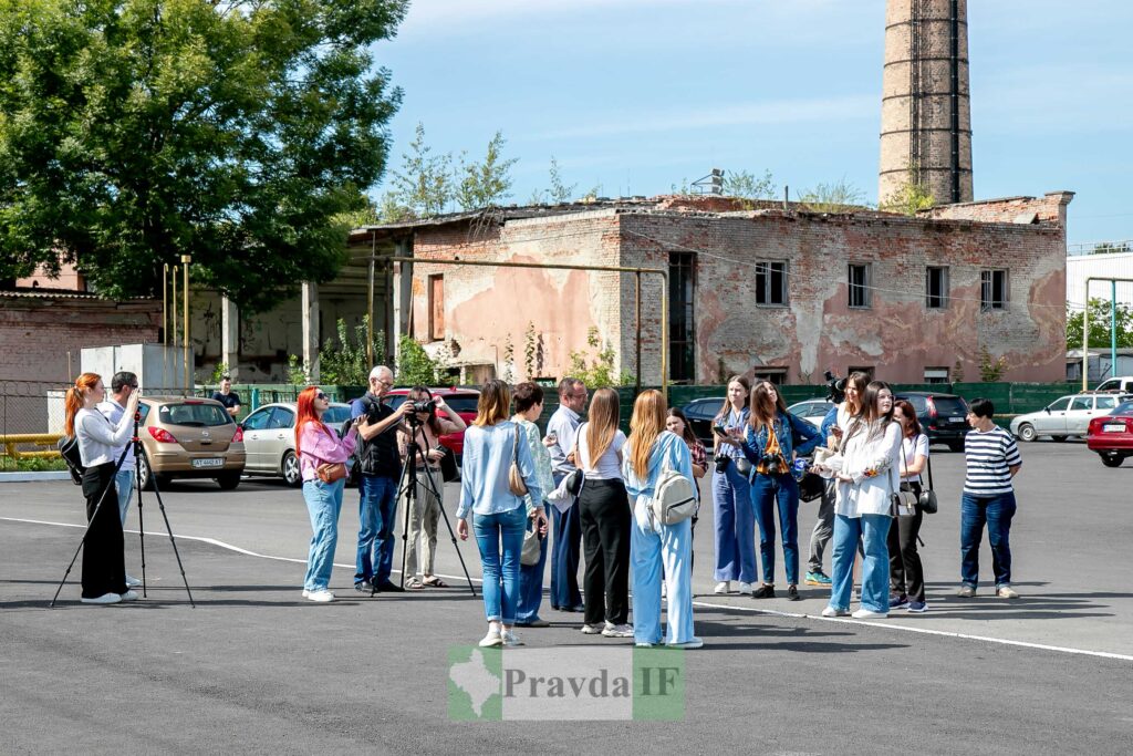 Група журналістів фотографує перед старою будівлею.