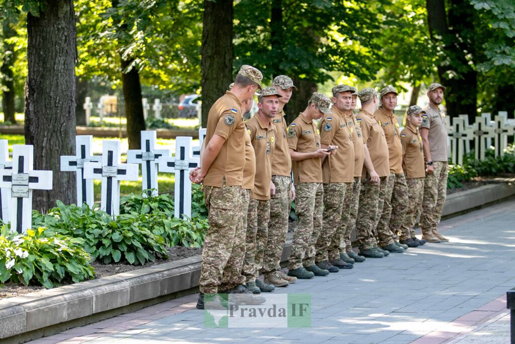Військові вшанування на кладовищі серед дерев та хрестів.