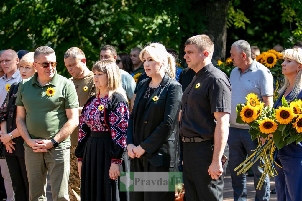 Люди з соняшниками на вулиці під час заходу.