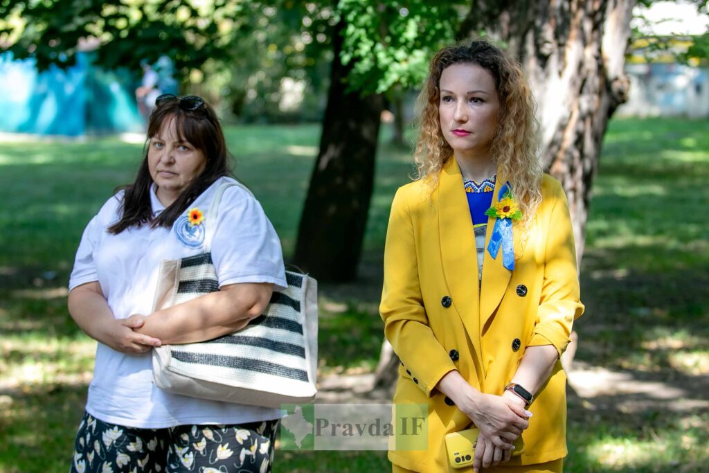 Дві жінки стоять у парку, соняшники на одязі.