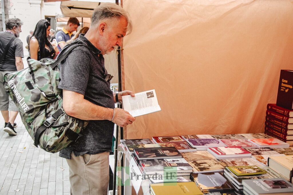Чоловік читає книгу на вуличному книжковому ярмарку.