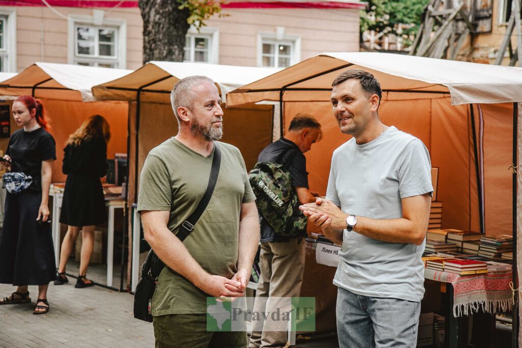 Люди спілкуються на вуличному книжковому ярмарку.