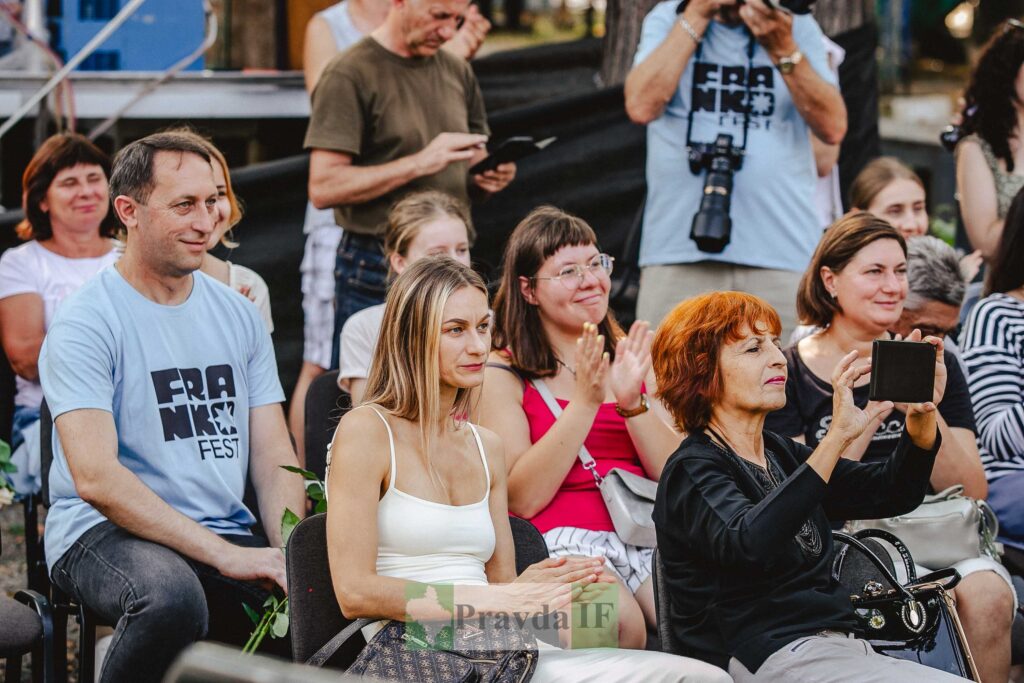 Люди на мистецькому заході, усміхаються та аплодують.