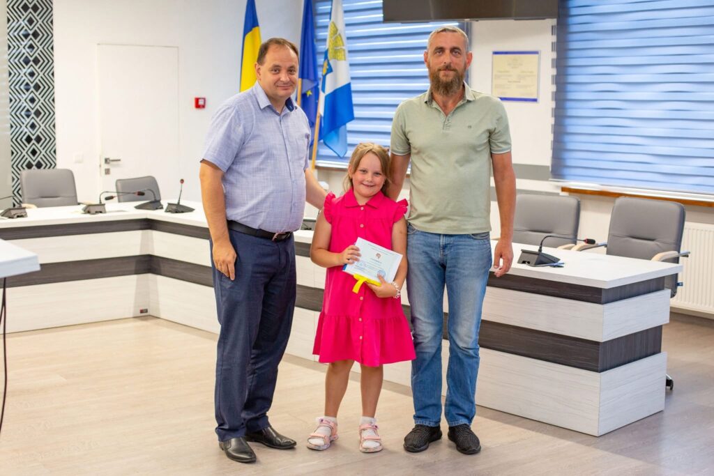Дівчина вручає диплом у кабінеті державної установи.