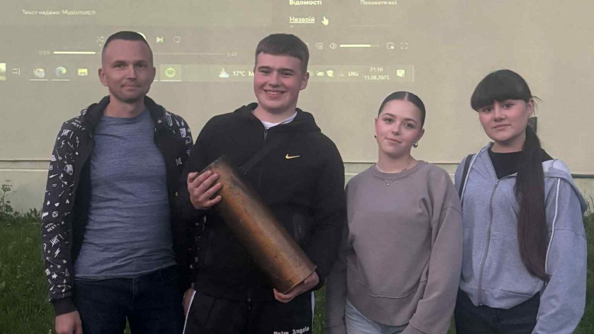 Четверо людей з великим металевим предметом.