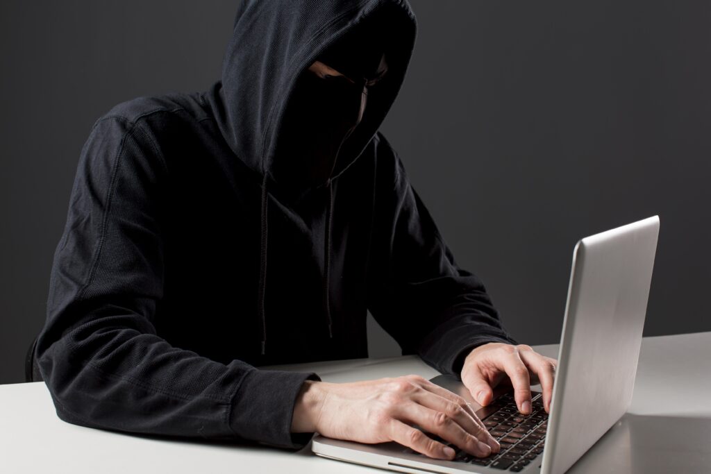 Людина в капюшоні працює на ноутбуці
