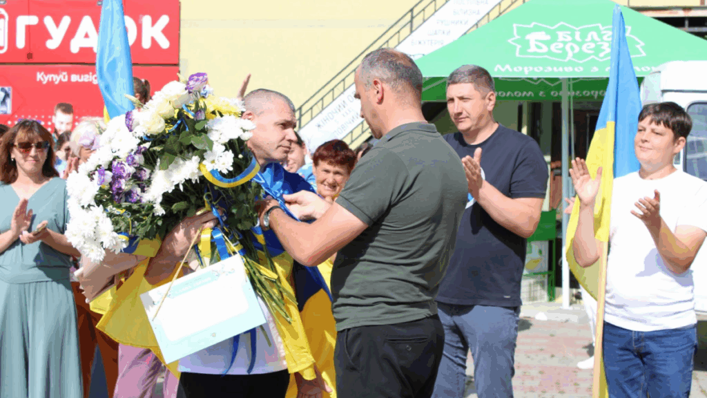 Людина отримує квіти та нагороду на святі.