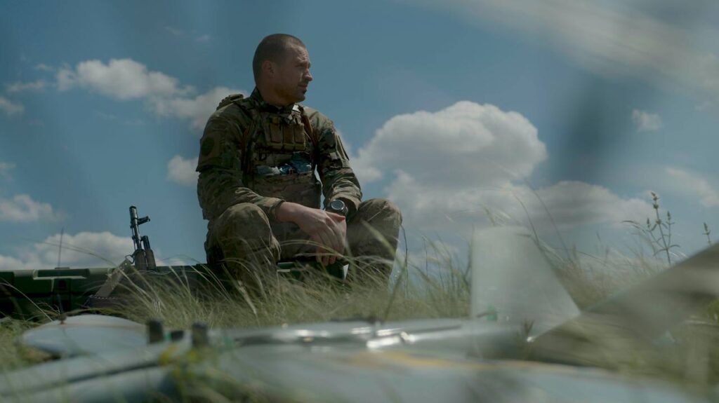 Український солдат відпочиває в полі під небом.