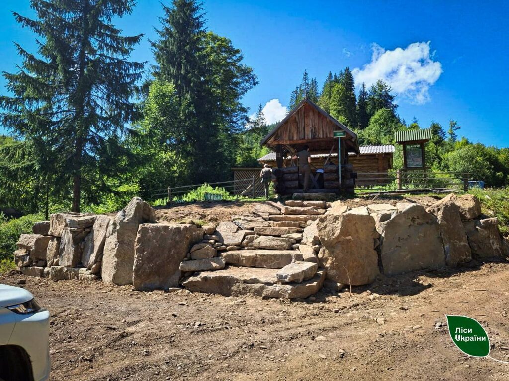 Лісова хатина серед зеленої природи та каменю.
