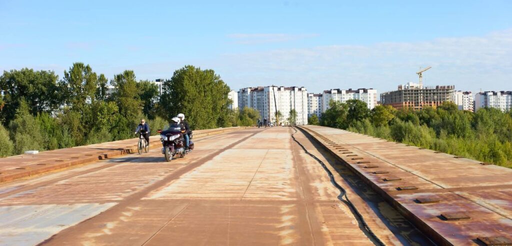 Люди на мосту, мотоцикл і велосипедисти.