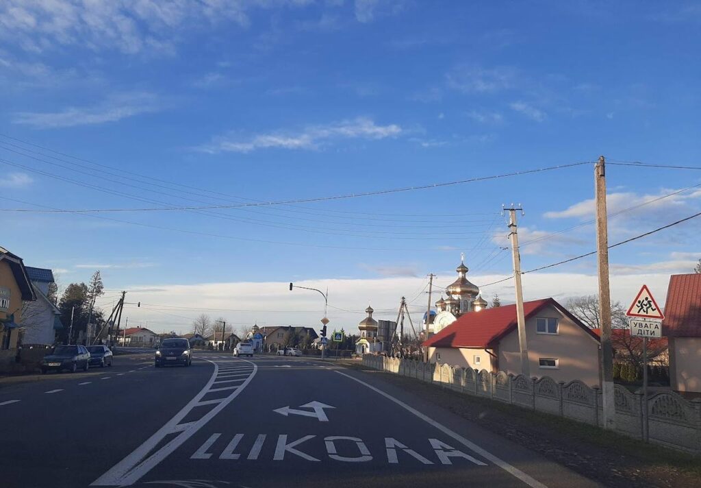 Дорога в селі з церквою та дорожнім знаком.