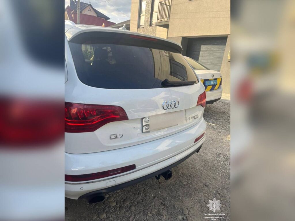 Білий Audi Q7 на ґрунтовій дорозі біля дому.