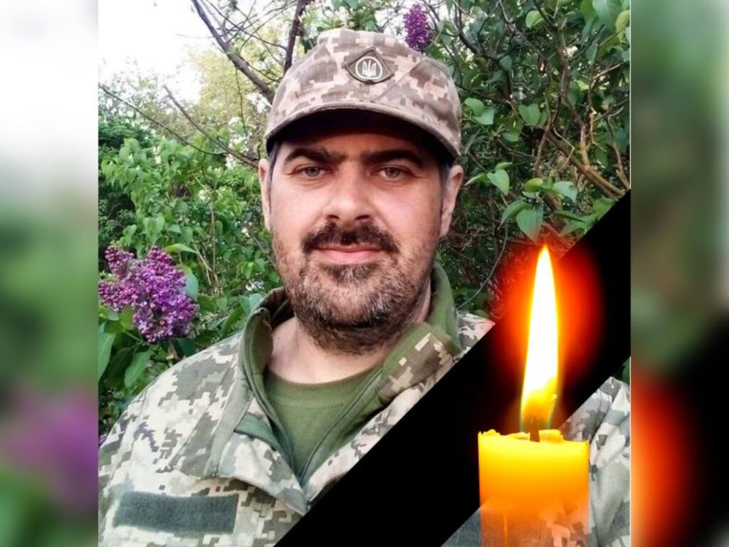 Чоловік у військовій формі зі свічкою пам'яті.