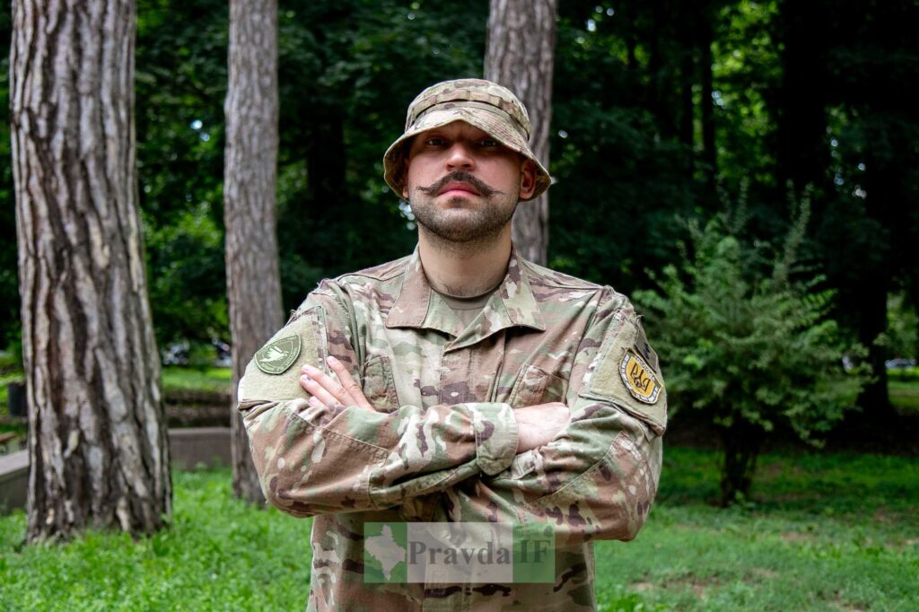 Військовий у камуфляжі стоїть у лісі.