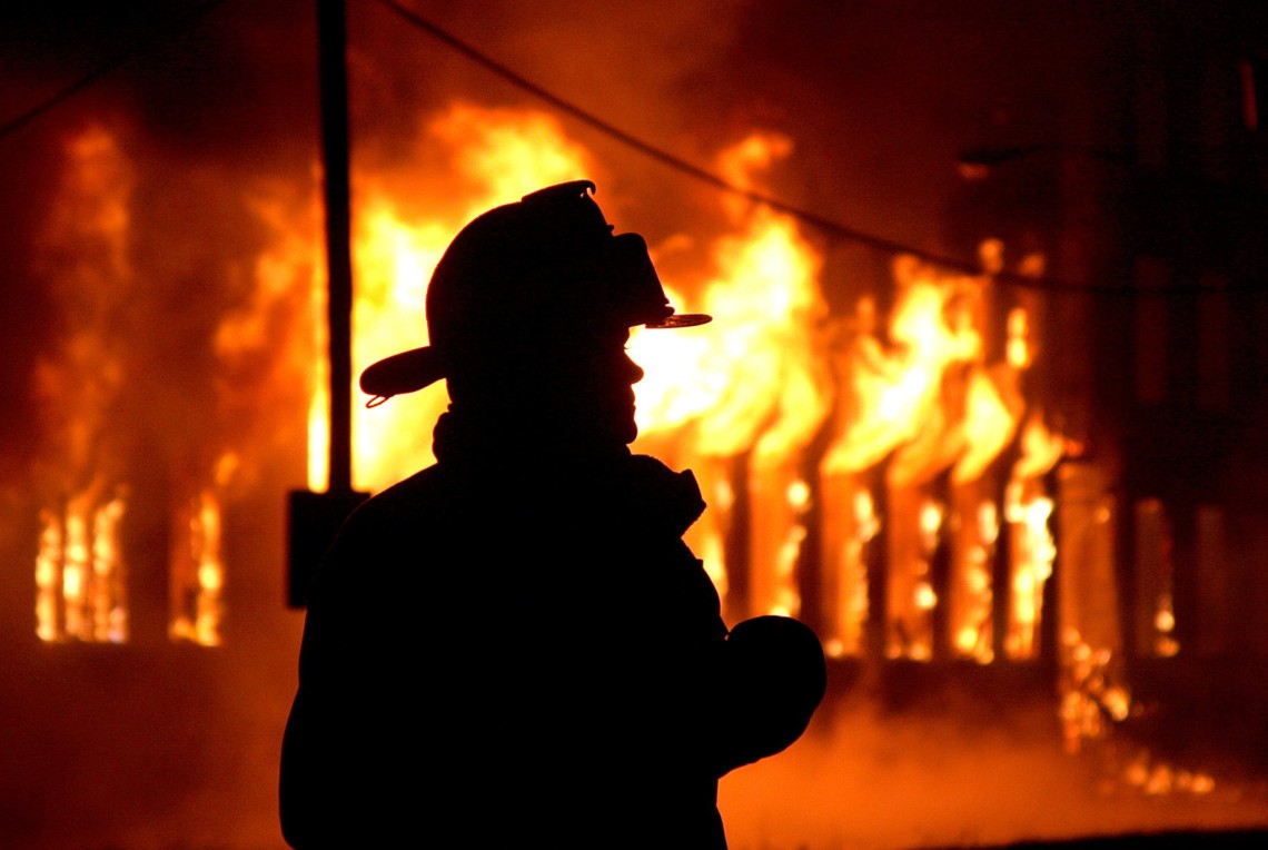 Пожежник біля палаючої будівлі вночі