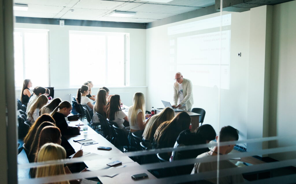 Лекція у світлому класі з багатьма студентами.