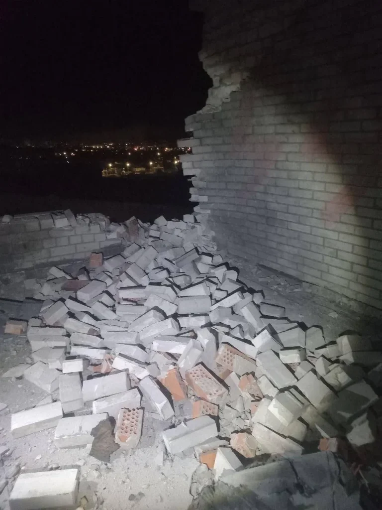 Зруйнована цегляна стіна вночі, вид на місто.