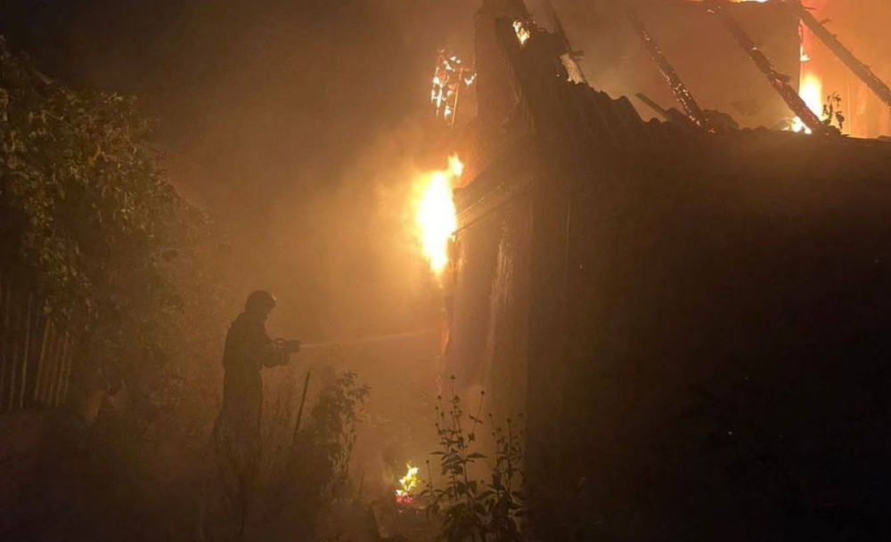 Пожежник гасить вогонь на даху будівлі
