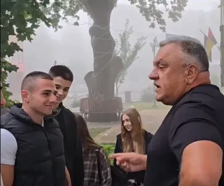 Група людей спілкується на вулиці біля дерева.
