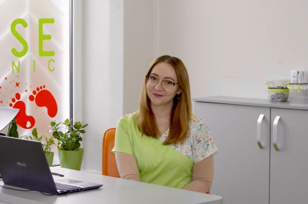 Жінка в медичному кабінеті біля столу