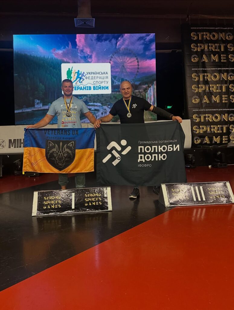 Двоє чоловіків з прапорами на змаганні в Україні.