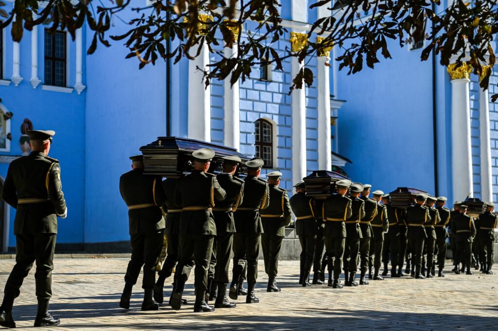 Військові несуть труни біля церкви в Україні.