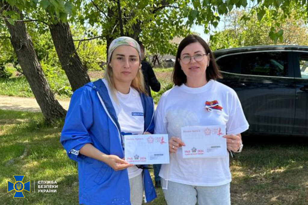 Дві жінки тримають документи на природі.