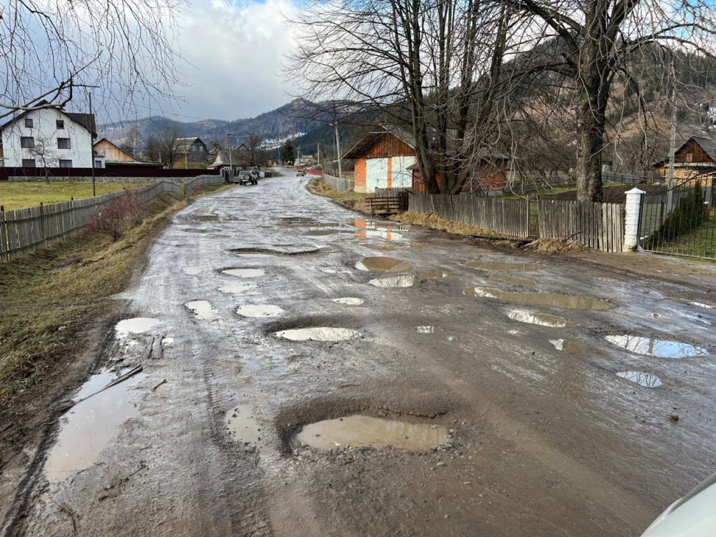 Розбита дорога з калюжами в селі, весна