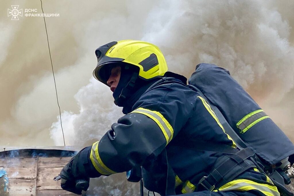 Пожежник бореться з пожежею, густий дим навколо.