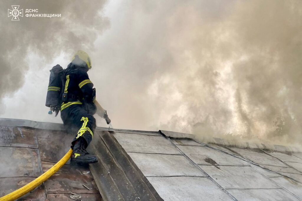 Пожежник гасить вогонь на даху будівлі.