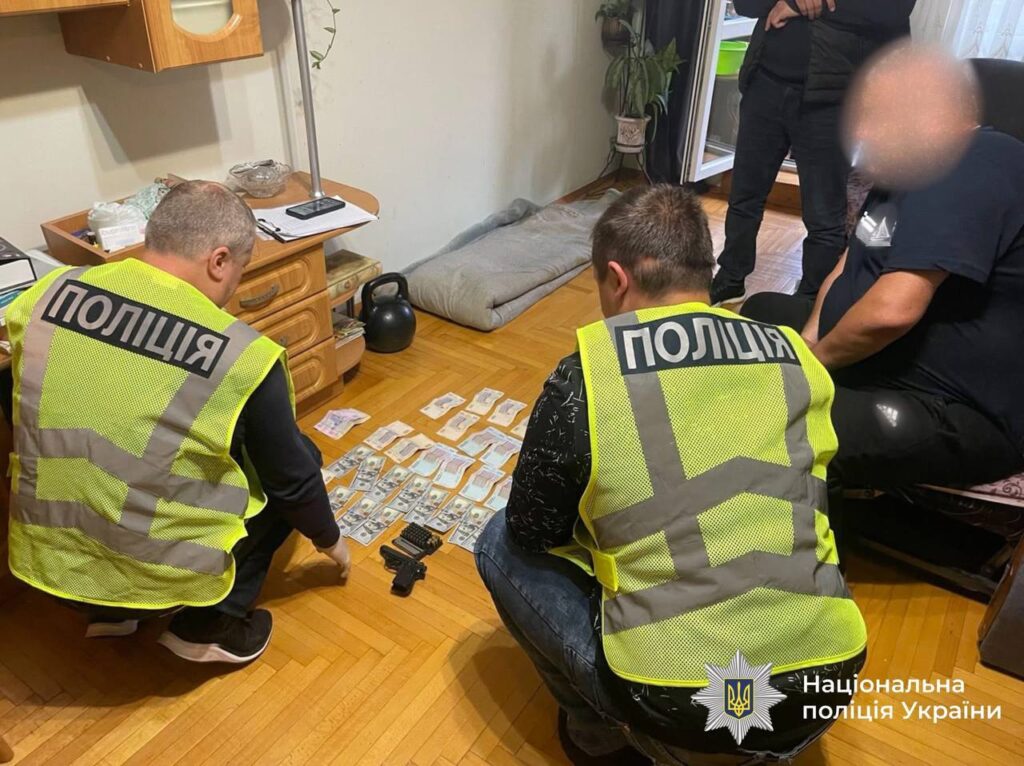 Поліцейські досліджують гроші та речові докази на підлозі.