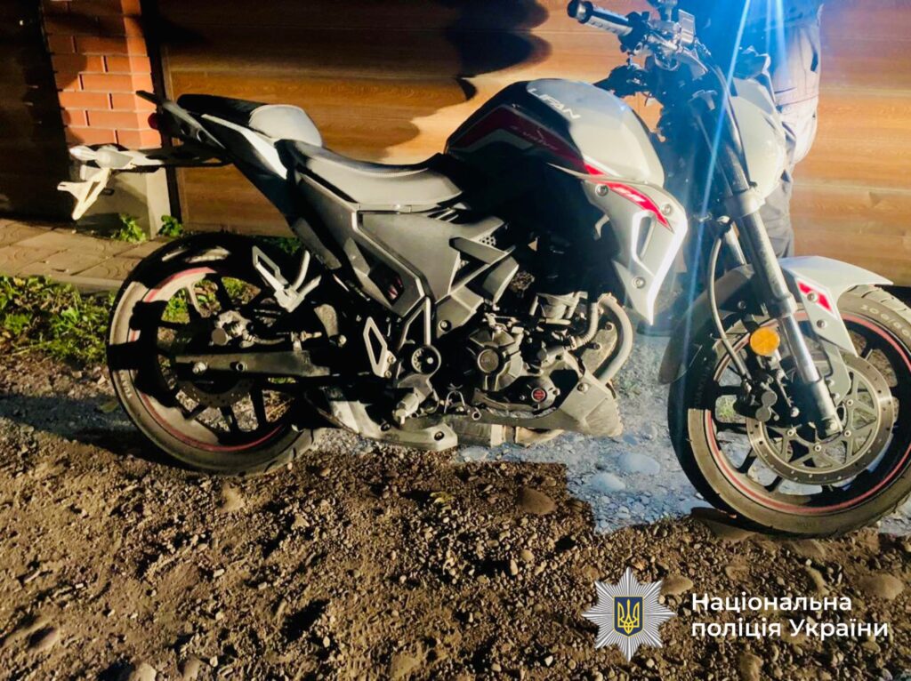 Мотоцикл на ґрунтовій дорозі біля будівлі.