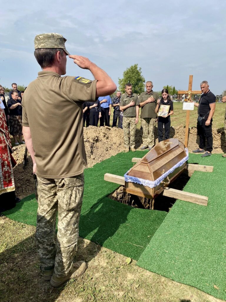 Військовий віддає честь біля труни на похороні.