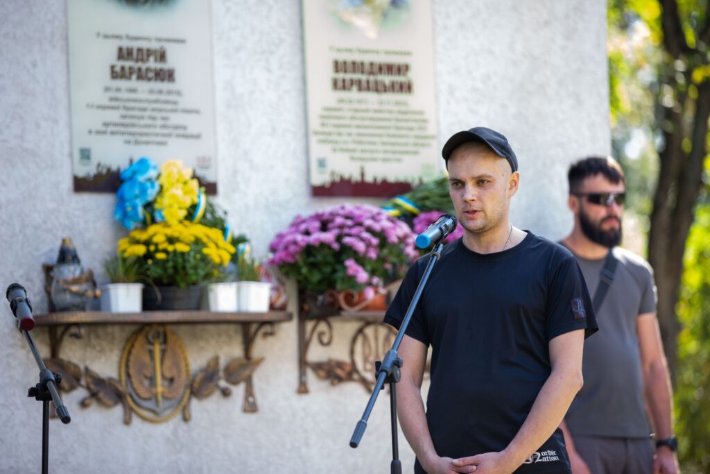 Чоловік виступає біля пам'ятної дошки вшанування.