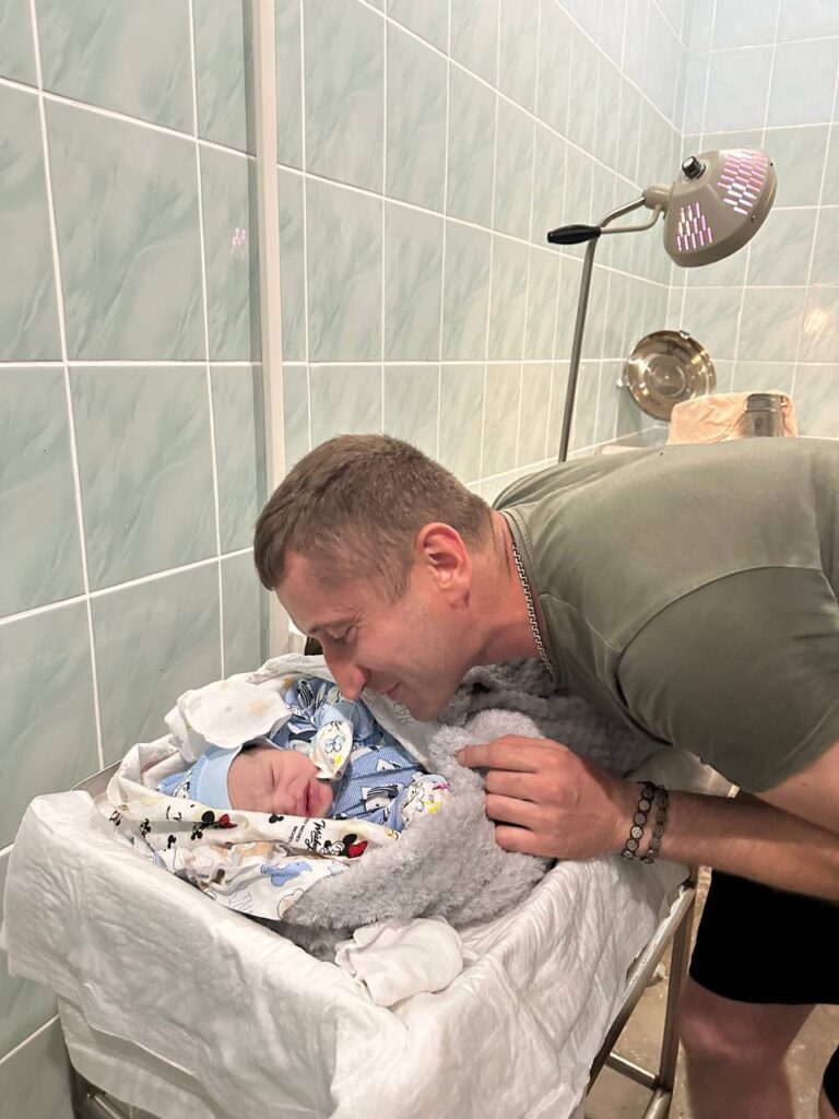 Батько нахиляється над новонародженим у лікарні